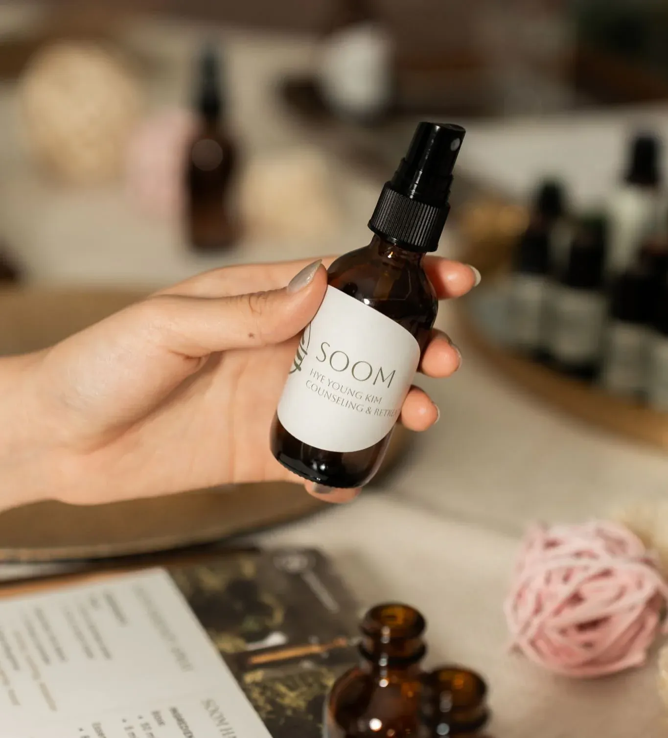 A hand holding a Soom-branded amber aromatherapy spray bottle